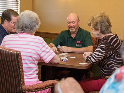 Residents participating in a card game with staff