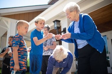 Silvercrest Properties LLC, assisted living in St. Louis Park, MN — Seniors interacting with children in a sunny outdoor setting