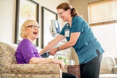 Caregiver assisting a smiling resident in a cozy lounge
