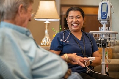 A nurse smiling and interacting with a resident in a common area