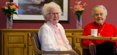 Two senior women smiling in a common area