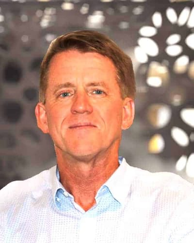 A man smiling against a blurred background
