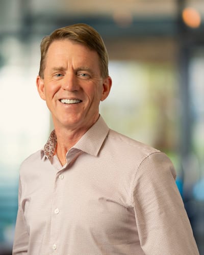A smiling man with short hair in a light shirt