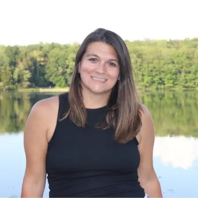 Woman by a lake with trees in the background