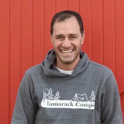 A smiling man wearing a Tamarack Camps hoodie