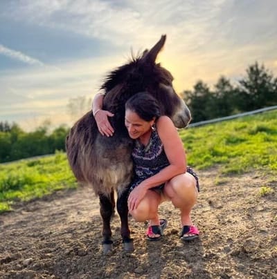 A woman hugging a donkey in an outdoor setting
