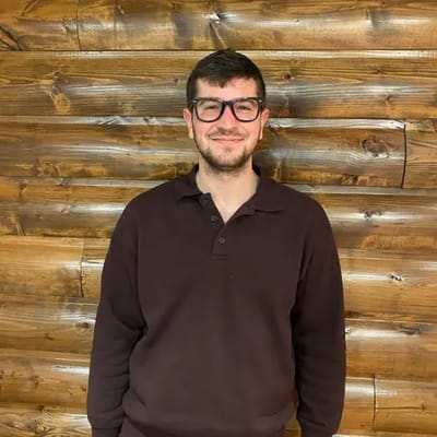 Man smiling in front of a wooden wall
