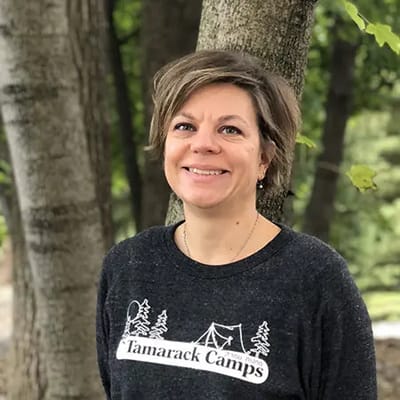 Staff member posing outdoors in a wooded area