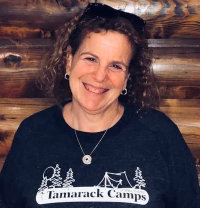 Smiling woman wearing Tamarack Camps sweatshirt