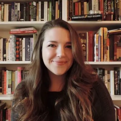 Person smiling in front of a bookshelf
