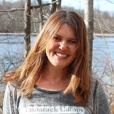 A woman smiling outdoors near a body of water