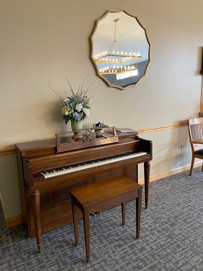 Straits Area Senior Living Community, assisted living in St. Ignace, MI — Piano with a decorative mirror and flower arrangement