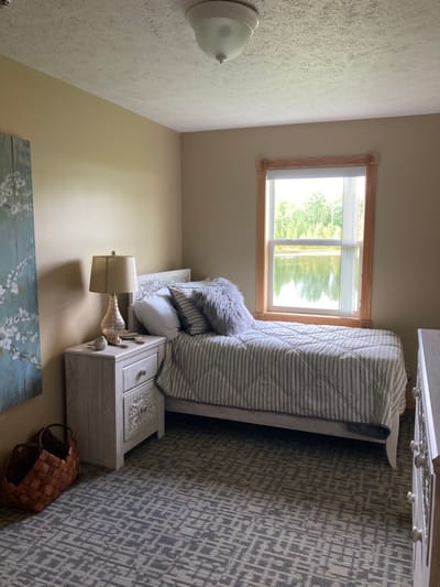 Straits Area Senior Living Community, assisted living in St. Ignace, MI — Cozy bedroom with lake view and decorative elements