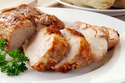 Slice of roast pork on a plate with garnish