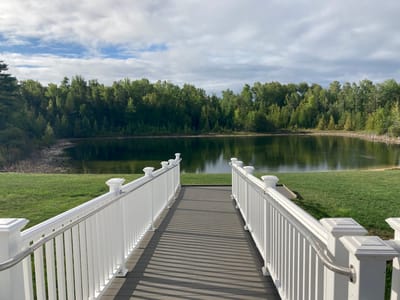 Straits Area Senior Living Community, assisted living in St. Ignace, MI — Bridge leading to a serene pond surrounded by trees