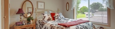Elmhurst Commons Apartments, assisted living in Braham, MN — Cozy bedroom with floral decor and natural light
