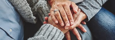 Two pairs of hands holding each other warmly