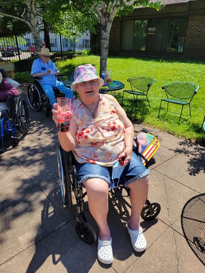 Resident enjoying a drink outside in a garden area