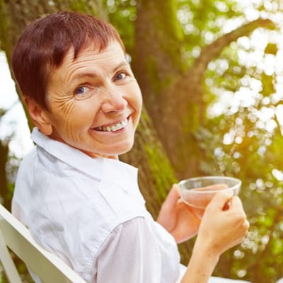 Senior woman enjoying a drink outdoors in a garden