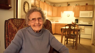 A smiling resident sitting in an armchair in a cozy interior