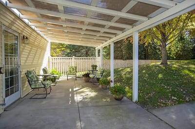 Covered outdoor seating area with chairs and plants