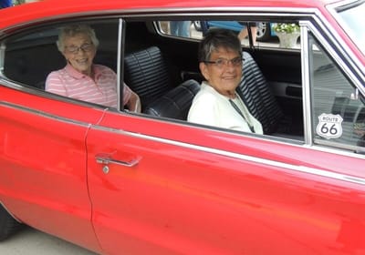 Two residents enjoying a ride in a classic car