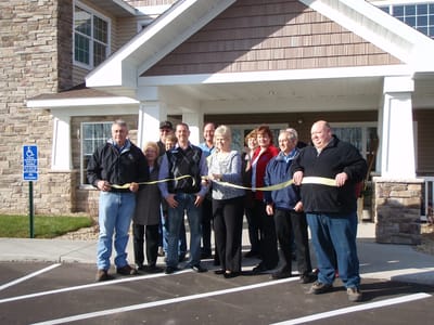 Group ribbon-cutting ceremony at facility entrance