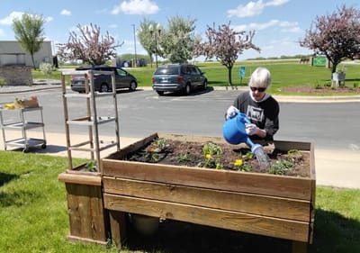 Resident gardening outdoors in a community garden bed