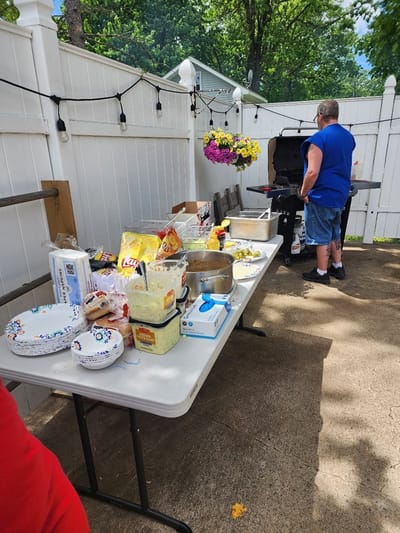 Barbecue setup in an outdoor space with food and a resident