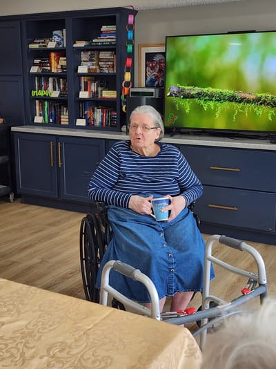 Resident in a wheelchair enjoying a drink in a common area