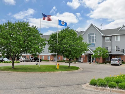 Exterior view of a senior living facility with trees and flags