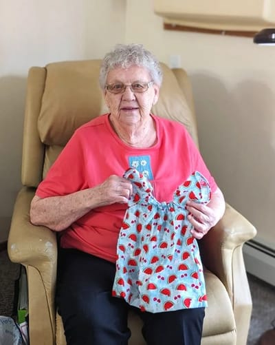 Resident holding a colorful handmade garment in their room