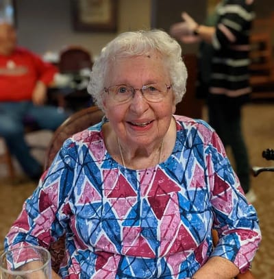 Resident smiling in a colorful sweater in a common area