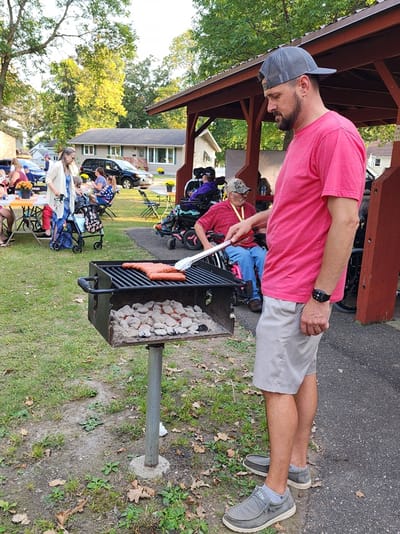 A staff member grilling food for residents in an outdoor setting