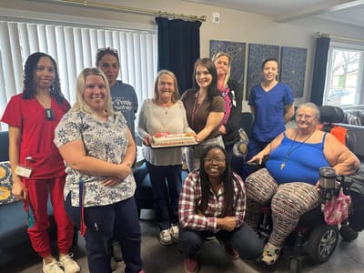 Residents and staff celebrating with a cake in a common area