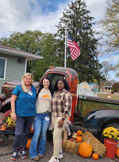 Staff and residents posing with pumpkins in an outdoor area