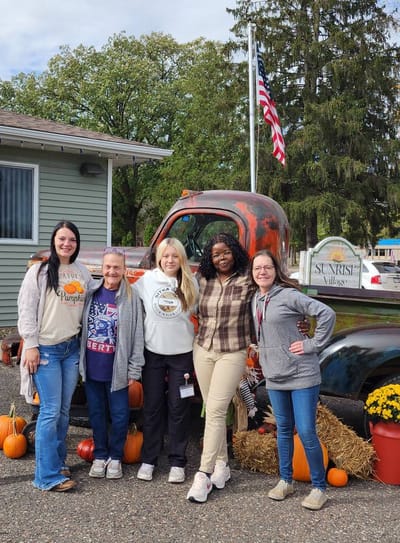 Staff and residents posing outside with autumn decorations