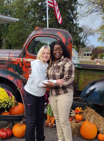 Two people posing with pumpkins and an old truck