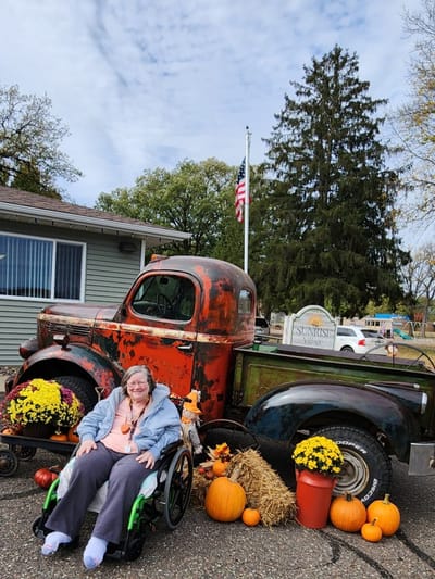 Resident posing with a vintage truck and fall decorations