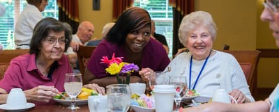 Residents enjoying meals with staff in a dining room