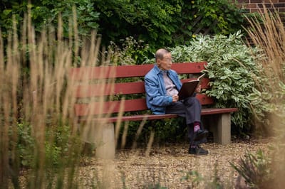 A resident enjoying a book in a garden area