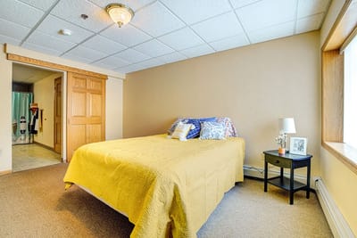A cozy bedroom with a yellow quilt and decorative pillows