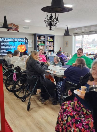 Residents enjoying Halloween songs and snacks in the activity room