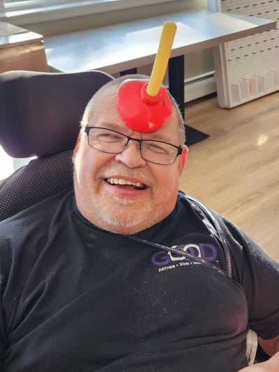 Resident enjoying a playful moment with a plunger on his head