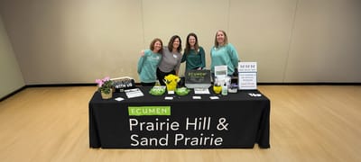 Four staff members at a welcoming table with promotional materials
