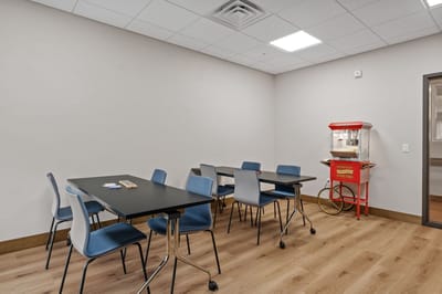 Interior activity room with tables and a popcorn machine
