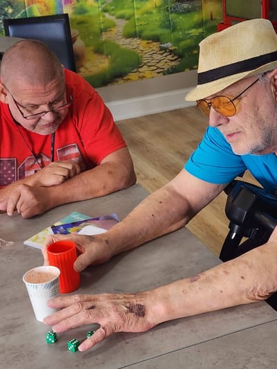 Two residents playing dice at a table