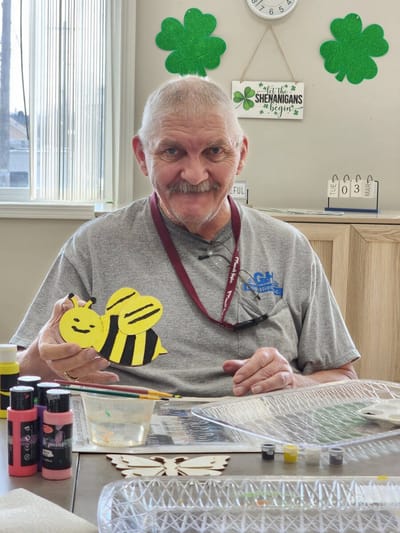 Resident enjoying an art activity with a painted bee