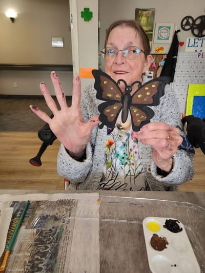 Resident holding a butterfly craft project.