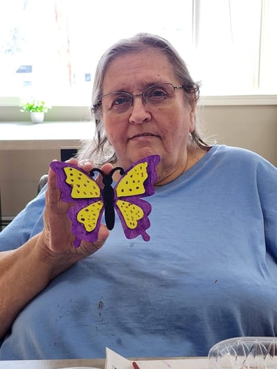 Resident holding a colorful butterfly craft